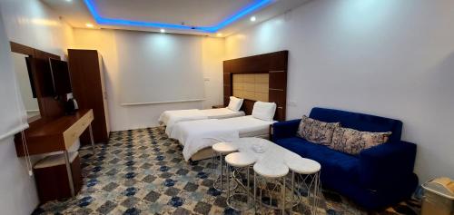 Hotat bani tamim的住宿－أباهي للوحدات السكنية الحوطة，酒店客房,设有两张床和一张蓝色的沙发