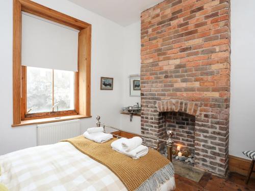 a bedroom with a brick fireplace and a bed at West Point Lynas Lighthouse Keeper's Cottage in Amlwch