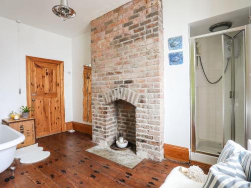 a living room with a brick fireplace and a sink at West Point Lynas Lighthouse Keeper's Cottage in Amlwch