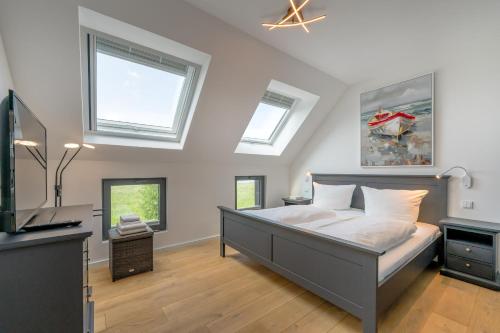 a bedroom with a bed and a tv and windows at Lee - Haus am See in Streu