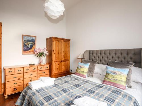 a bedroom with a bed and a dresser at East Point Lynas Lighthouse Keeper's Cottage in Amlwch