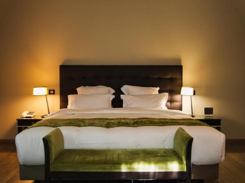 a large bed in a hotel room with two lamps at Amicitia - Hôtel & Restaurant in LʼIsle-Adam