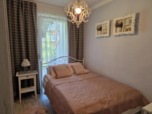a bedroom with a bed and a window with a chandelier at Apartament Klaudynka in Jantar