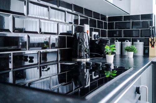 eine Küche mit schwarzen Fliesenwänden und einer schwarzen Arbeitsplatte in der Unterkunft Spacious house near City Centre -Sleeps 8 - Parking in Liverpool