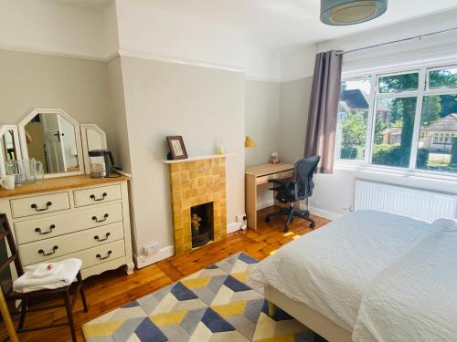 a bedroom with a bed and a desk and a fireplace at Ladram on Haroldslea in Horley