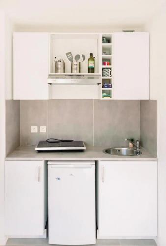 une cuisine avec des armoires blanches et un évier dans l'établissement Studio cozy et moderne dans résidence à Nice, à Nice