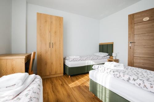 a room with three beds and a wooden cabinet at Dom do wynajęcia z tarasem i ogrodem, balia, ognisko in Sandomierz