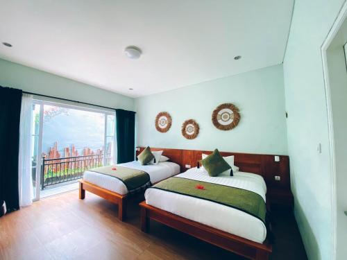 two beds in a room with a window at The Green Home Bali in Denpasar