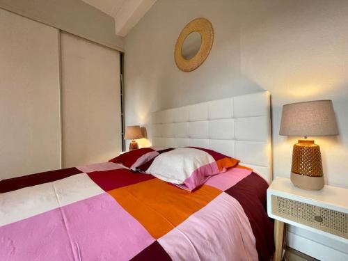 ein Schlafzimmer mit einem farbenfrohen Bett und einer Uhr an der Wand in der Unterkunft Charleston chic ※ centre-ville in Carcassonne