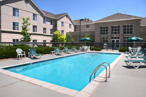 a swimming pool at a hotel with chairs and umbrellas at Homewood Suites by Hilton Colorado Springs North USAFA in Colorado Springs
