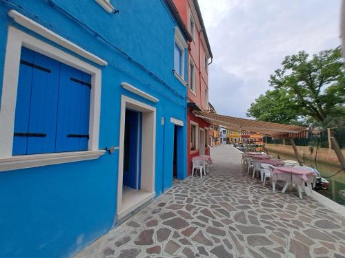 um edifício azul com mesas e cadeiras numa rua em Ca Jole em Burano