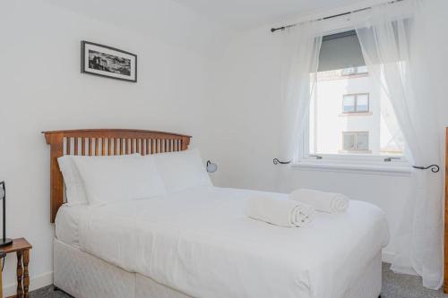 a bedroom with a white bed and a window at GuestReady - Restful stay near Edinburgh Castle in Edinburgh