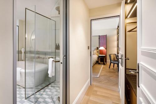 a bathroom with a glass door leading to a bedroom at Small Luxury Hotel Ambassador Zurich in Zürich