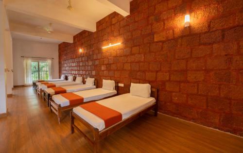 a row of beds lined up against a brick wall at Misty Heights by The Sanihara in Vayittiri