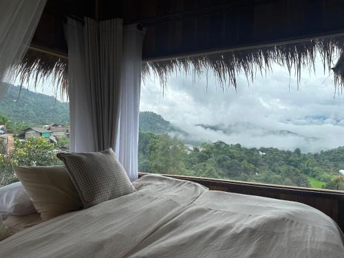 een bed in een kamer met een groot raam bij Wanna’s house in Ban Huai Khai