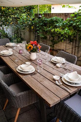 a wooden table with plates and glasses and flowers on it at Zug Zugersee Lake- and Mountainview House with charm in Zug