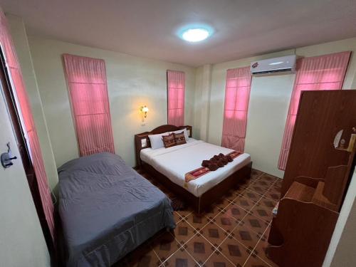a small bedroom with two beds and pink curtains at Mae Somboon House in Lamai