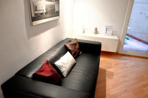 ein schwarzes Ledersofa im Wohnzimmer mit Kissen in der Unterkunft Homenfun Barcelona Sagrada Familia Glories in Barcelona