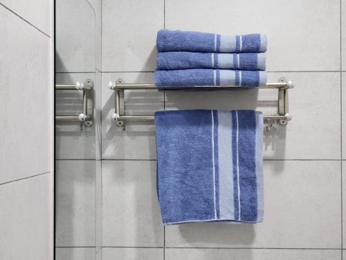 a towel rack with blue towels on it in a bathroom at Kuching Town DeSunset - Balcony with Amazing View in Kuching