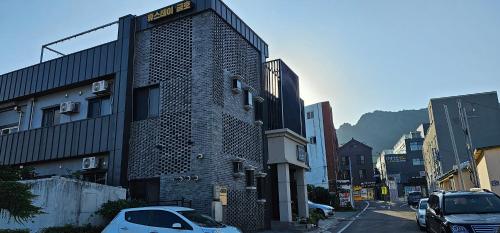 a tall brick building with cars parked on a street at Hotel HueStay-KeumHo in Seogwipo