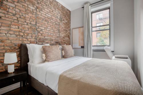 a bedroom with a brick wall and a bed at Murray Hill 2br w wd nr groceries hospital NYC-1228 in New York