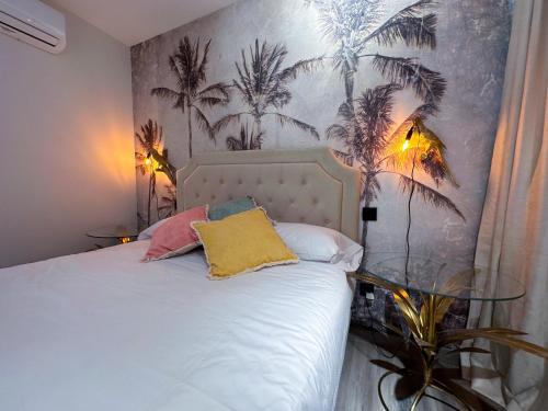 sypialnia z białym łóżkiem z palmami na ścianie w obiekcie NATURA ROOMS 