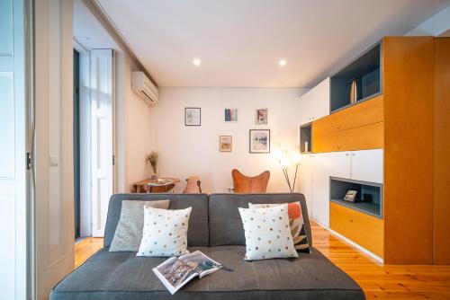 - un salon avec un canapé gris et des oreillers dans l'établissement JOIVY Modern flat with patio in central Porto, à Porto