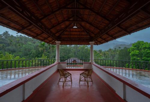 two chairs sitting on the balcony of a house at Misty Heights by The Sanihara in Vayittiri