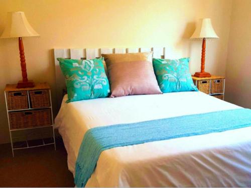 a bedroom with a bed with blue pillows and two lamps at Peaceful Place in Port Nolloth