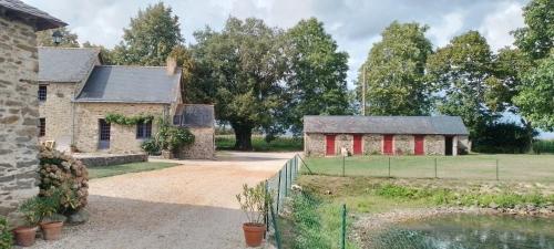 une ancienne maison en pierre avec une clôture et un étang dans l'établissement Gîte la Petite Gilardière, à Gennes-sur-Glaize