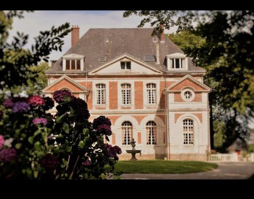 una gran casa de ladrillo con flores delante en Grand gîte pour 28 personnes dans un château en Normandie en Beuzevillette