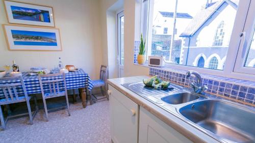 a kitchen with a sink and a table and a window at Pencoed in Llanbedrog