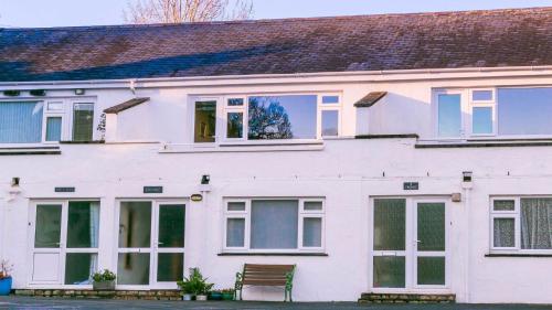 a white house with a bench in front of it at Pencoed in Llanbedrog