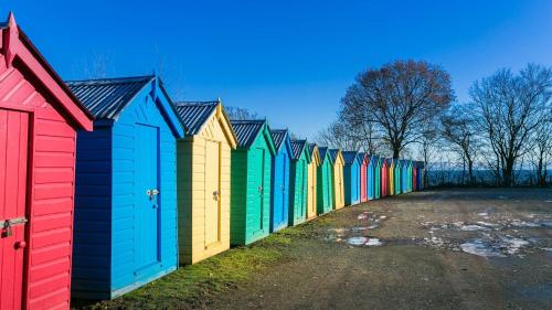 a row of colorful beach huts lined up in a row at Pencoed in Llanbedrog