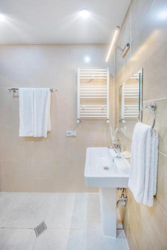 a white bathroom with a sink and a mirror at Solo Grand Boshuri Hotel Wellness Resort in Qvemo Boshuri