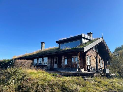 una casa vieja con techo de hierba en una colina en Solsetra - Mountain Majesty Family Log Cabin en Hovden