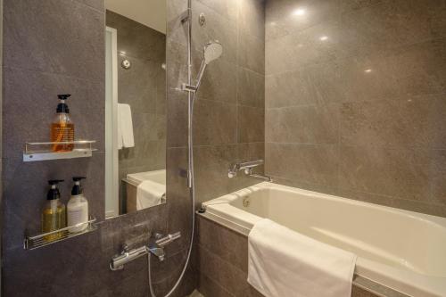 a bathroom with a shower with a tub and a sink at Tosei Hotel Cocone Tsukiji Ginza Premier in Tokyo