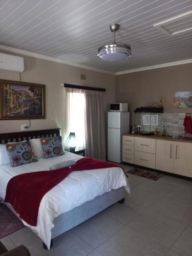 a bedroom with a large bed and a kitchen at Esperance Guesthouse in Upington