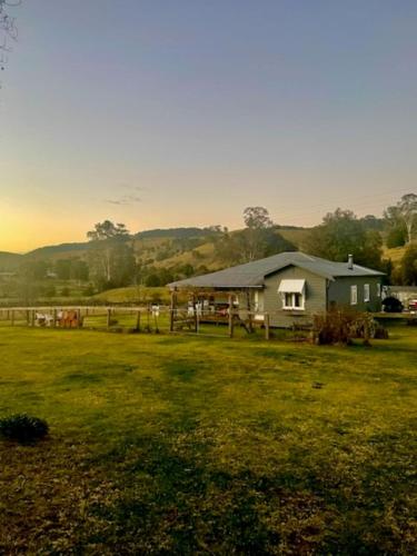 a small house in a field with a fence at Little Farmhouse Near The Dairy in Warranulla