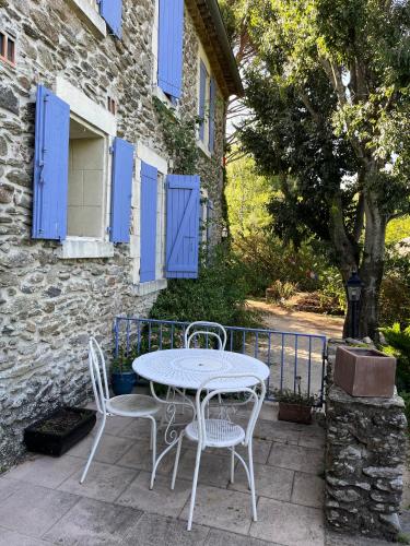 une table et des chaises sur une terrasse avec volets bleus dans l'établissement Gîte exploration, à Gravières