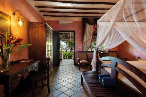 a bedroom with a bed and a table and a desk at Hotel Club Dongwe in Pingwe