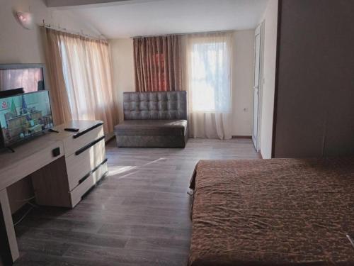Habitación de hotel con cama, TV y silla en Apartments Devora 1 & bar & restaurant en Varna