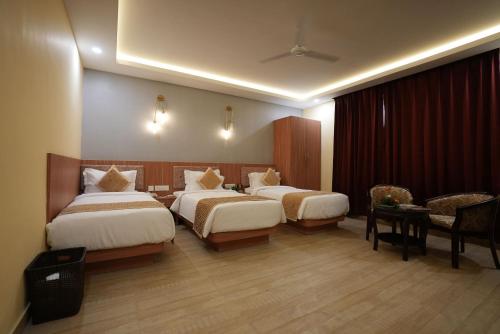um quarto de hotel com duas camas e uma mesa e cadeiras em The Royal Bihar em Patna