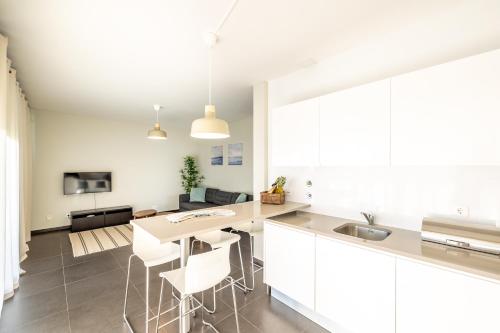 Una cocina con gabinetes blancos y una mesa y sillas. en Carina Villas, en Lourinhã