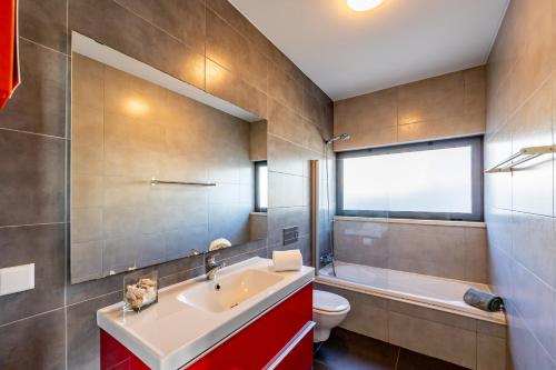 baño con lavabo y aseo y ventana en Carina Villas, en Lourinhã