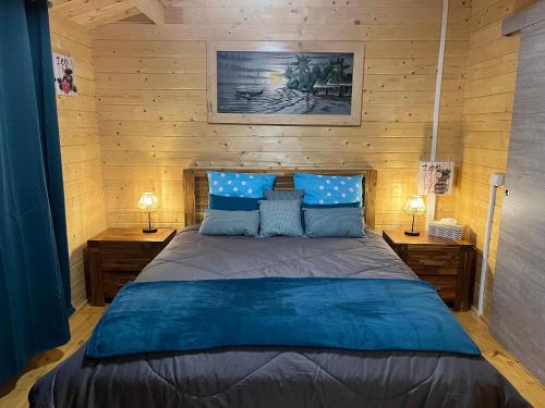 una camera da letto con un grande letto con cuscini blu di Les Chalets de Marie & Stéph - Jacuzzi SPA privatif sans vis à vis , vue mer a Saint-Denis