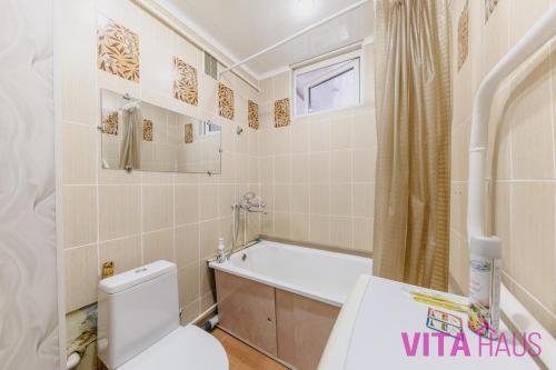 a bathroom with a toilet and a tub and a sink at Квартира в центре Золотой in Petropavlovsk