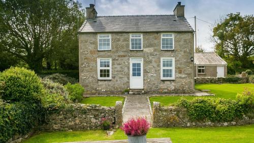 an old stone house with a garden in front of it at Aber in Moelfre