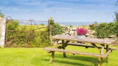 a wooden picnic table with a vase of flowers on it at Aber in Moelfre
