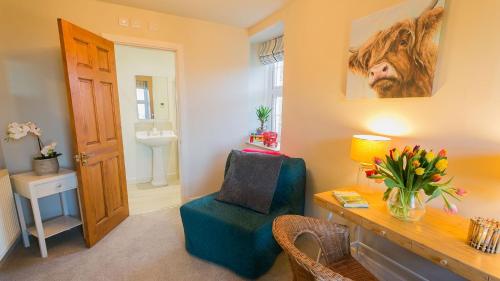 a living room with a blue chair and a desk at Aber in Moelfre